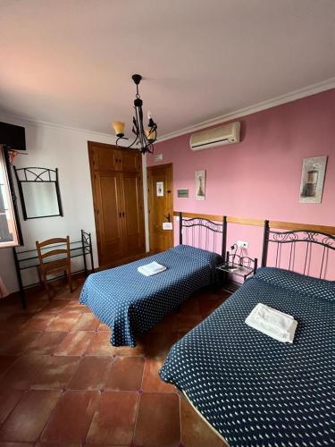 2 camas en una habitación con paredes rosas en Casa Kini, en Cazalla de la Sierra