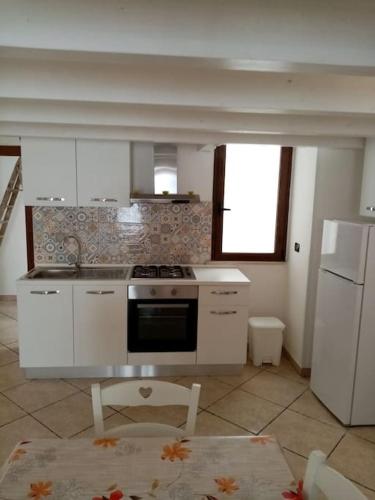 a kitchen with white cabinets and a stove top oven at Paola's house in Copertino