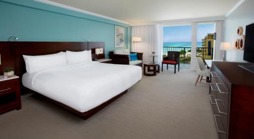 um quarto com uma grande cama branca e uma sala de estar em Aruba Marriott Resort & Stellaris Casino em Palm-Eagle Beach