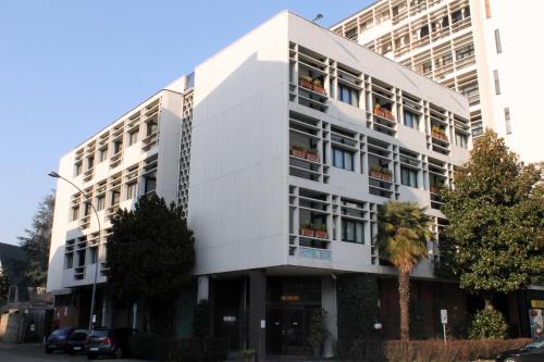 a white building with a palm tree in front of it at iH Hotels Milano Eur - Trezzano sul Naviglio in Trezzano sul Naviglio
