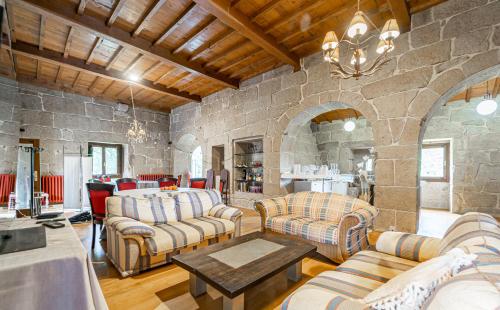 a living room with couches and a stone wall at Casa Rural Pazo San Damian in Amoeiro