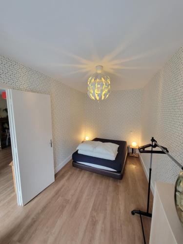 une chambre avec un lit et un lustre dans l'établissement Petite maison 40M² à PAIMPONT (35), à Paimpont