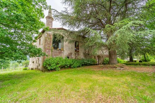 an old stone house with a clock tower in a field at Casa Rural Pazo San Damian in Amoeiro