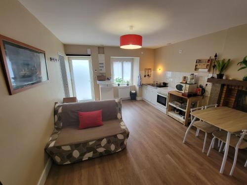 salon z kanapą i stołem oraz kuchnia w obiekcie Petite maison 40M² à PAIMPONT (35) w mieście Paimpont