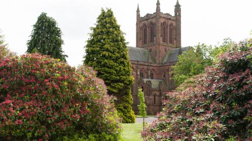 an old church with a tower and a bunch of trees at Holiday Inn Dumfries by IHG in Dumfries
