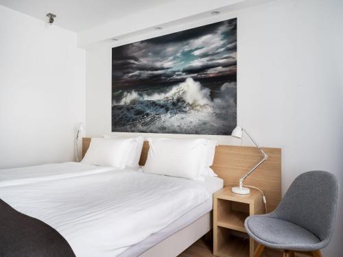 a bedroom with a bed and a chair and a painting at Storm Hotel by Keahotels in Reykjavík