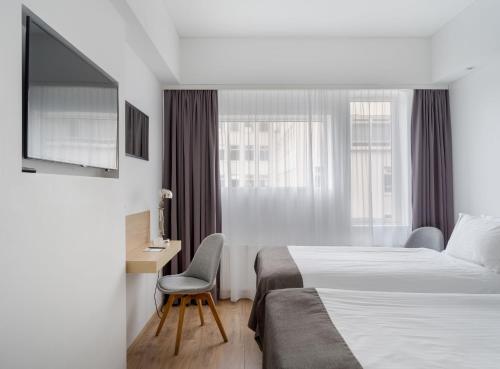 a hotel room with a bed and a desk and a television at Storm Hotel by Keahotels in Reykjavík