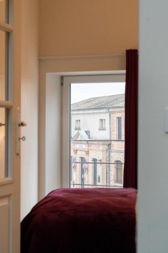 a window with a view of a building at Sur la place , centre village cosy & calme 2CH in Lapeyrouse-Fossat