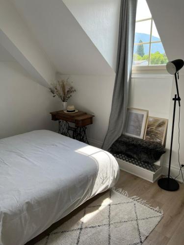 une chambre avec un lit blanc et une fenêtre dans l'établissement les chambres de pauline appartements avec climatisation et spa parking moto garage vélo, à Albertville