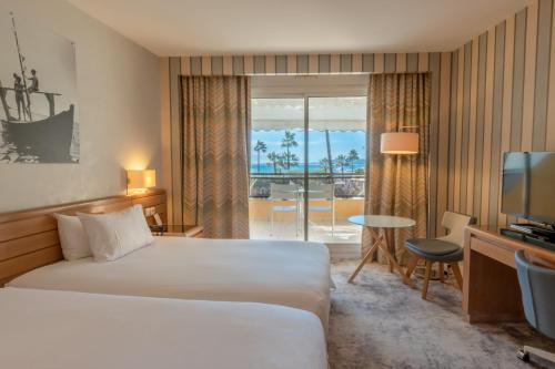 a hotel room with a bed and a television at Holiday Inn Nice - Port St Laurent by IHG in Saint-Laurent-du-Var