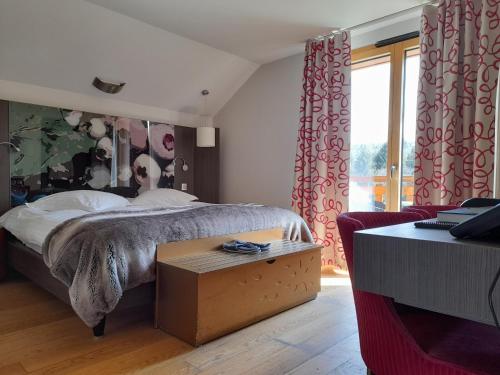 a bedroom with a bed and a table and a window at Hôtel L'Etang du Moulin By Céline in Bonnétage