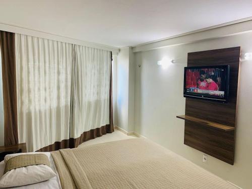 a bedroom with a bed and a television on a wall at Home service na praia de Cabo Branco in João Pessoa