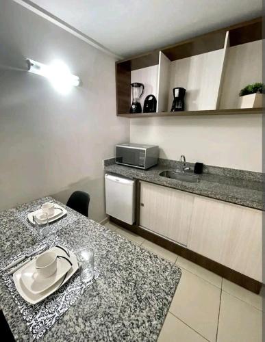 a kitchen with a counter and a table and a sink at Home service na praia de Cabo Branco in João Pessoa