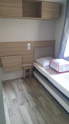 a small bedroom with a bed and a wooden floor at Amira 6 personnes in Saint-Jean-de-Monts