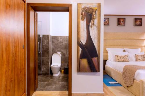 a bedroom with a bed and a bathroom with a toilet at Legend Boutique Hotel in Kigali