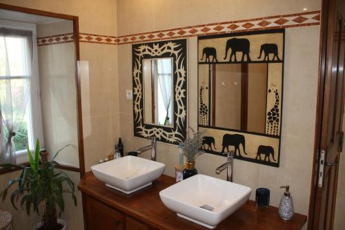 La salle de bains est pourvue de 2 lavabos et de 2 miroirs. dans l'établissement La Douce France Trianon, à Chinon