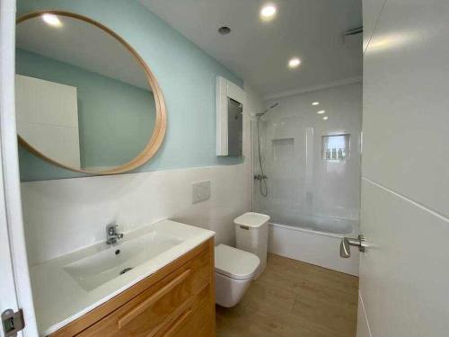 a bathroom with a sink and a toilet and a mirror at Apartamento Sunset con vistas Playa de Los Locos in Suances