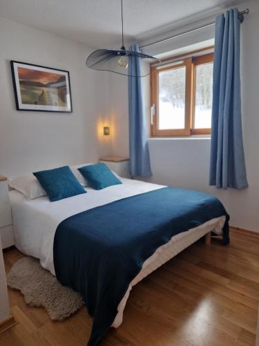 une chambre avec un grand lit avec des rideaux bleus dans l'établissement Appartement tout confort montagne et lac Léman, à Thollon-les-Mémises
