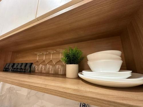 a shelf with plates and wine glasses and a plant at Twin Galaxy city view 2 Bedroom with balcony in Johor Bahru