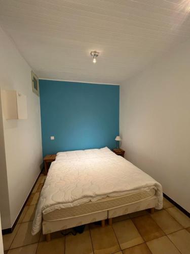 une chambre avec un grand lit avec un mur bleu dans l'établissement 2TOAU8 Charmant studio proche plage, à Collioure