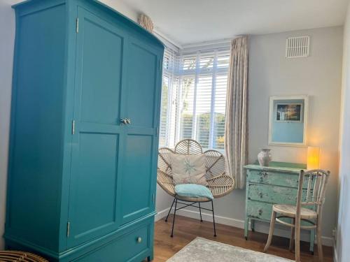 a blue cabinet in a room with a chair and a desk at Blue Anchor House - Seaview, Hot Tub Apartments in Blue Anchor