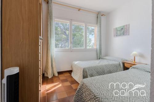 a bedroom with two beds and a window at Villa Elvira by MarCalma in Les tres Cales