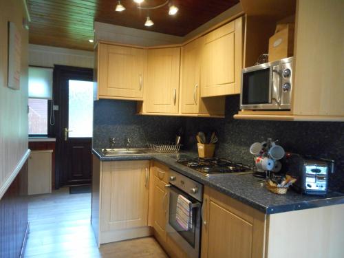 a kitchen with wooden cabinets and a stove top oven at Bluebell Lodge 5 with Hot Tub in Newton Stewart