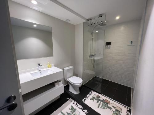 La salle de bains est pourvue de toilettes, d'un lavabo et d'une douche. dans l'établissement Charmant F2 à SkyNui, piscine de 25m et vue mer, à Papeete