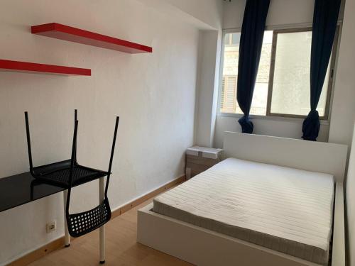 a small bedroom with a bed and a chair at Las Canteras 128 in Las Palmas de Gran Canaria