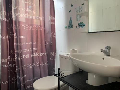 a bathroom with a sink and a toilet and a shower curtain at Las Canteras 128 in Las Palmas de Gran Canaria