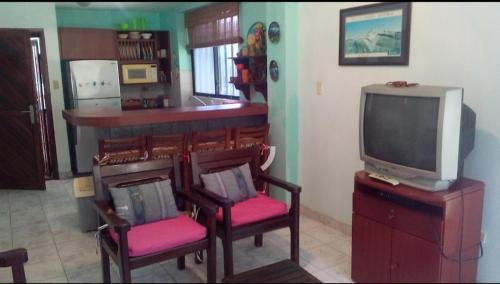 a living room with a tv and two chairs and a tv console at Costa Grande Tucacas Morrocoy in Tucacas
