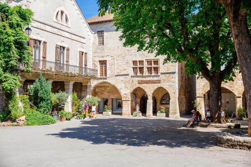 un patio de un edificio con personas sentadas en el suelo en La Maison des Pélerins Villeneuve, en Villeneuve-dʼAveyron