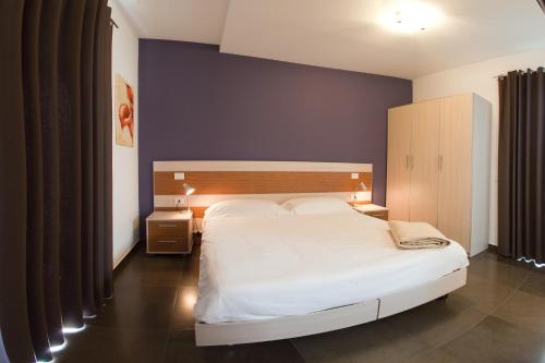 een slaapkamer met een wit bed en een blauwe muur bij Ragusa Inn in Ragusa