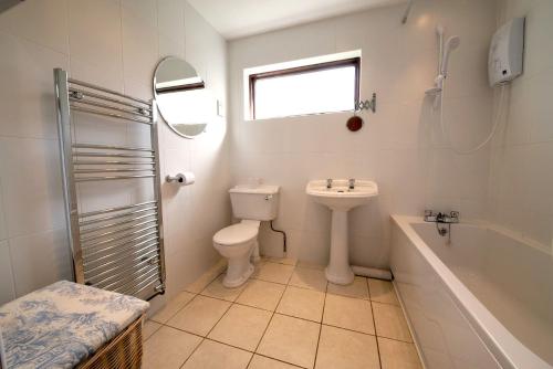 a bathroom with a sink and a toilet and a bath tub at Beck Yeat Cottage Coniston in Coniston