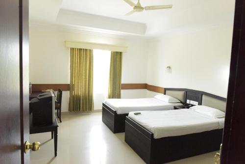 a hotel room with two beds and a television at Paray Village County in Kollengode