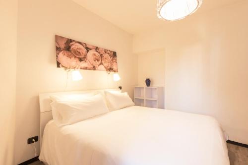 ein Schlafzimmer mit einem weißen Bett und einem Gemälde an der Wand in der Unterkunft Loppia Bay by Wonderful Italy in Bellagio