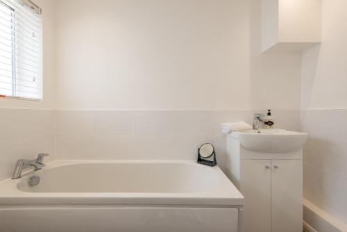 een witte badkamer met een bad en een wastafel bij Bede House in Monkwearmouth