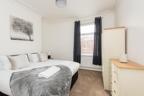 a bedroom with a bed and a dresser and a window at Bede House in Monkwearmouth