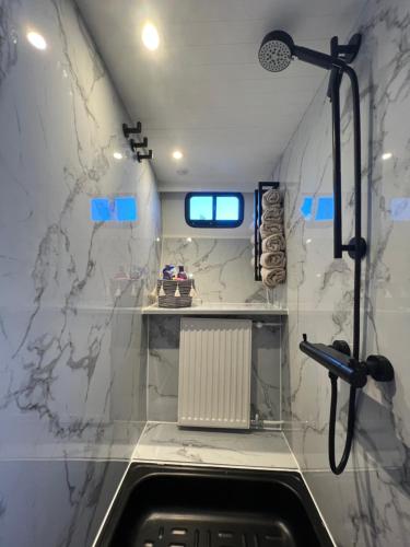 een badkamer met witte marmeren muren en een douche bij NEW - LITTLE IBIZA, on a lake near Amsterdam, with HOT TUB! in Vinkeveen