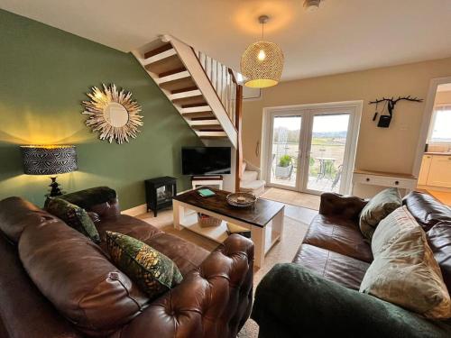 a living room with a leather couch and a staircase at Blue Anchor House - Seaview, Hot Tub Apartments in Blue Anchor