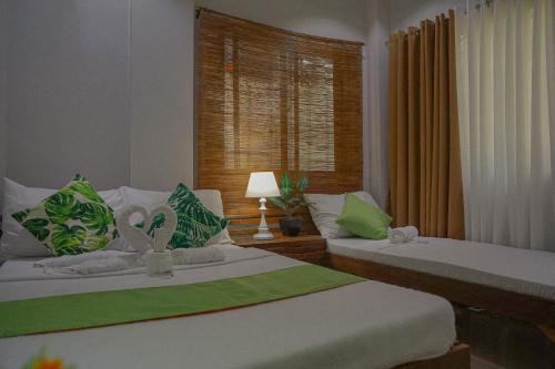 2 camas con almohadas verdes y blancas en una habitación en The Palms Resort & Bar, en San Narciso