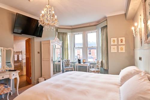 a bedroom with a large bed with a chandelier at Quilt and Croissants Guest House in Stratford-upon-Avon