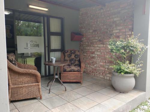 a patio with two chairs and a table and a brick wall at Ditsaleng Bed and Breakfast in Vanderbijlpark