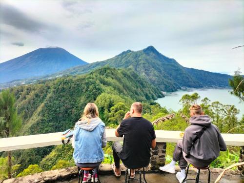 a group of people sitting on a railing looking at the mountains at Bali Sunrise Camp & Glamping in Kintamani