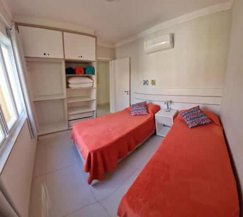 a bedroom with two beds with red sheets and a window at Apartamentos Vida Mansa in Bombinhas