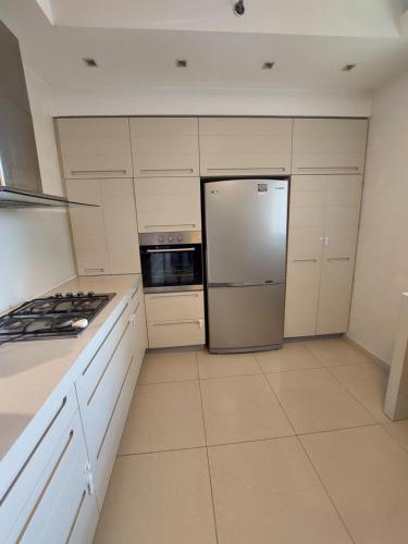 a kitchen with white cabinets and a stainless steel refrigerator at Exlusive apartments in Ashdod in Ashdod