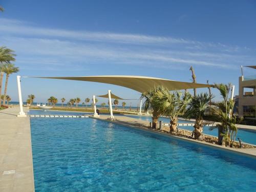 una piscina con un dosel y palmeras en Mangroovy - 1BR GF +2 wall beds Garden & Pool view, en Hurghada