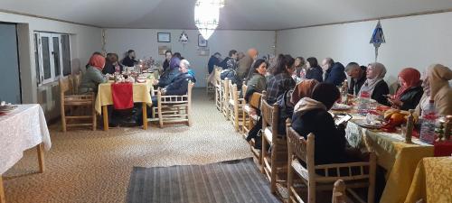 un gruppo di persone sedute ai tavoli in una stanza di Abdo Luxury Camp with Heating a Merzouga