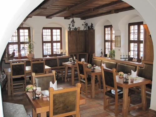 a restaurant with wooden tables and chairs and windows at Schloss Schänke garni in Bautzen