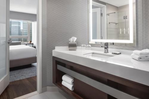 a bathroom with a sink and a bed and a mirror at Minneapolis Marriott City Center in Minneapolis